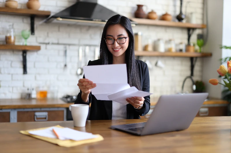 businesswoman happily reads a finance letter at her desk, managing paperwork in her office